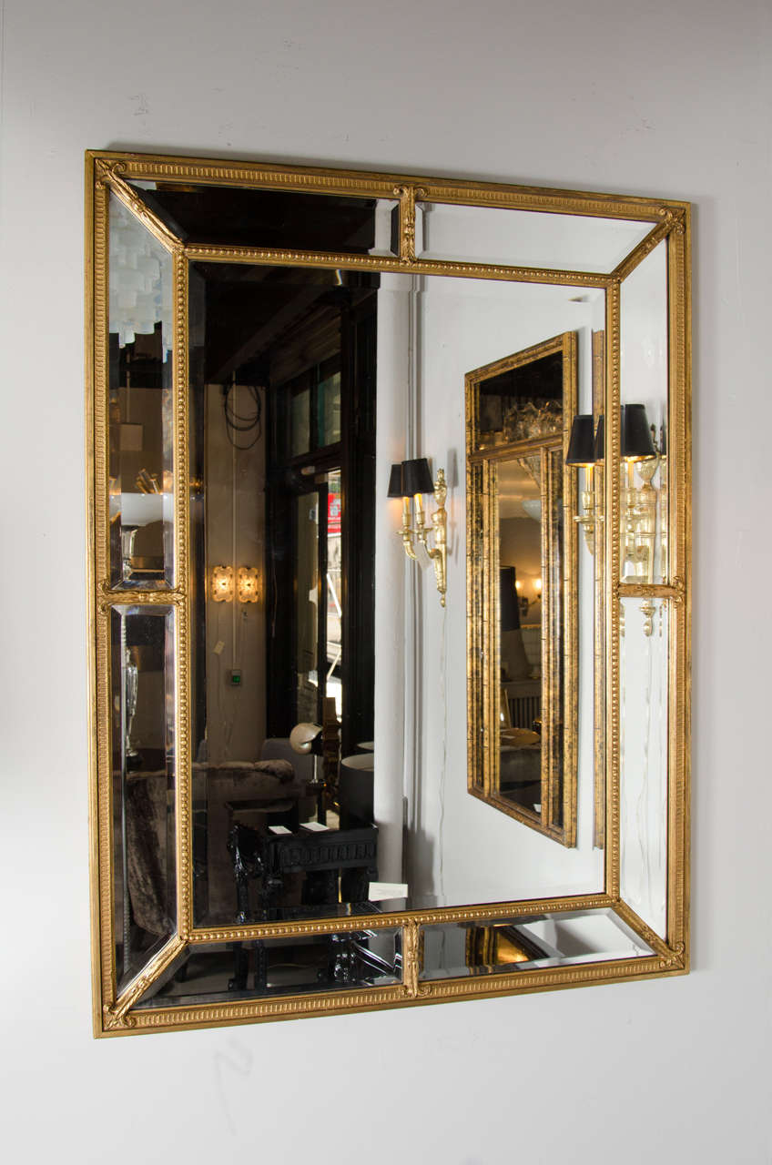 This Mid-Century Modern mirror with gilt beaded frame & Fleur de lys detailing. It has a segmented border with inset hand beveled mirror and the main mirror is also beveled. Can be hung horizontally or vertically.