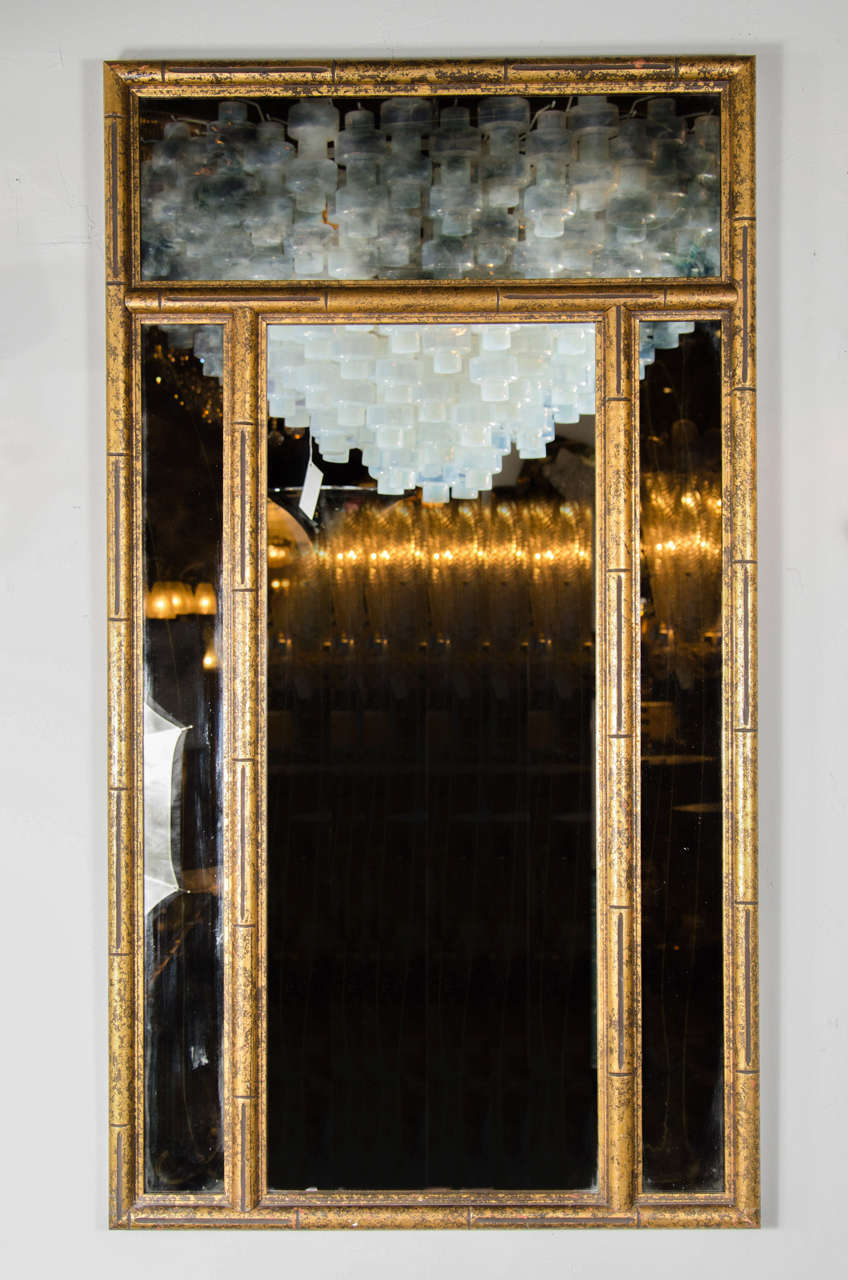 This Mid-Century Modern mirror features a border in stylized bamboo design with gilt finish, the outer panels are smoked mirror, the central panel is clear mirror. This mirror is perfect size for an entry , hallway or powder room and is in excellent