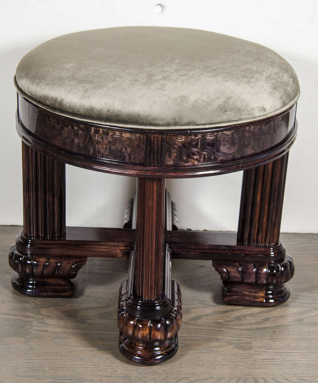 Art Deco stool in the style of Ruhlmann with X-form base and ribbed, column like legs that descend from its thick banding in ebonized Maple with fluted detailing.  The base of each ribbed, column like leg is capped with a stylized and intricate