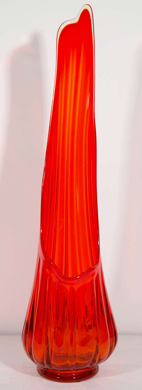 Midcentury architectural hand blown glass vase with amorphous column design. The vase is tall and has a footed base with ribbed or fluted details.  Glass has a striking and vibrant vermillion hue.