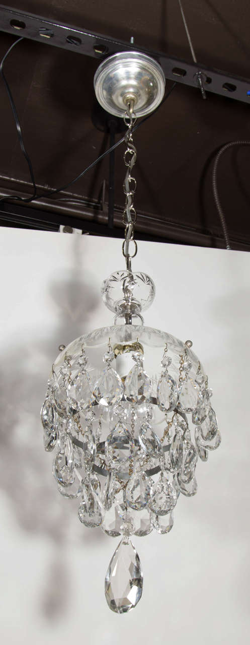 Elegant Hollywood era crystal chandelier with fine cut crystal pendants and with etched crystal glass dome and crystal canopy.  The chandelier has a circular form with three tiers of crystal pendants.  It features a chromed frame and fittings, as