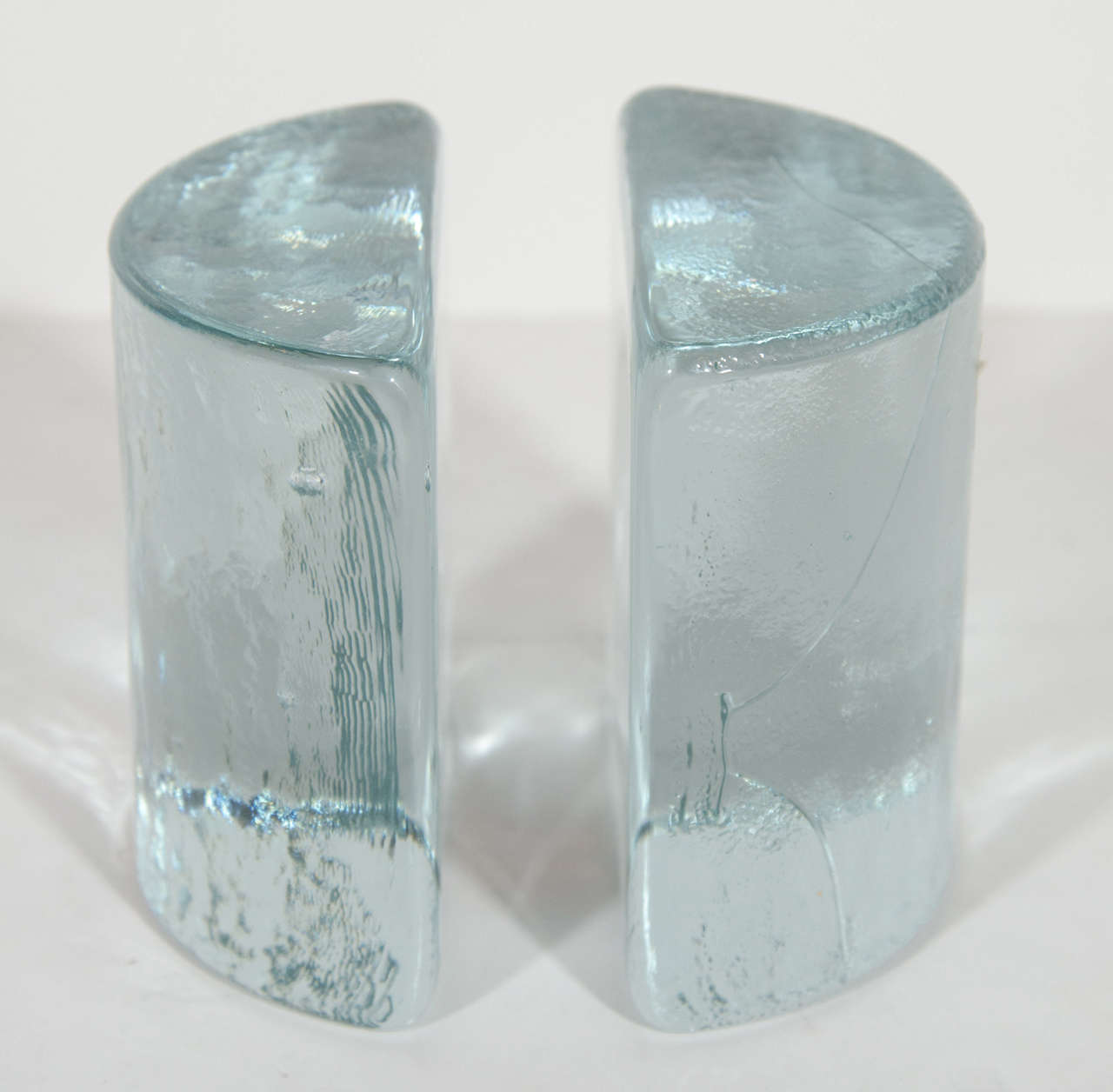 Pair of vintage modern individually hand blown glass bookends. The bookends are comprised of two half circles or demilune glass blocks with ice glass design. Can be used as decorative objects or desk accessory .  Signed Blenko.