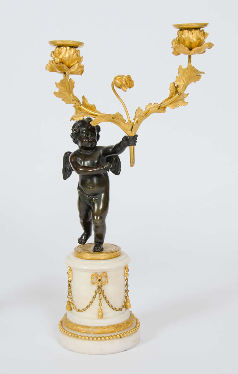 Louis XVI period, each of the bronze figures holding a two light ormolu branch, standing on a white marble base mounted with ormolu decoration in the Classical manner.
One is a Sprite, a fairy like spirit with small solid wings, the other is a