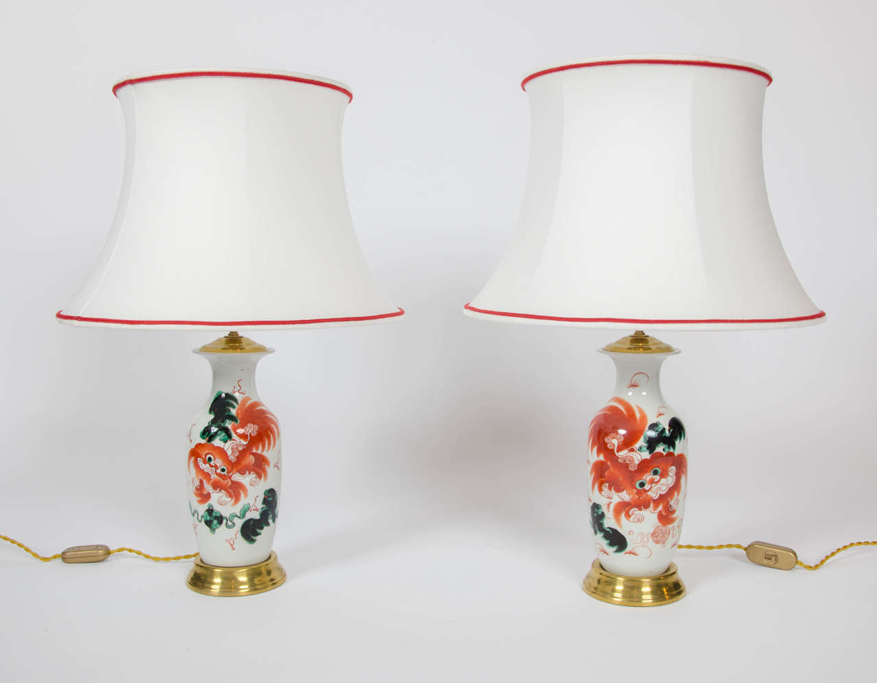 A very attractive pair of late 19th century Chinese vases now as table lamps, with a corresponding cup and cover. Depicting red dragons on a white background and green decoration. 