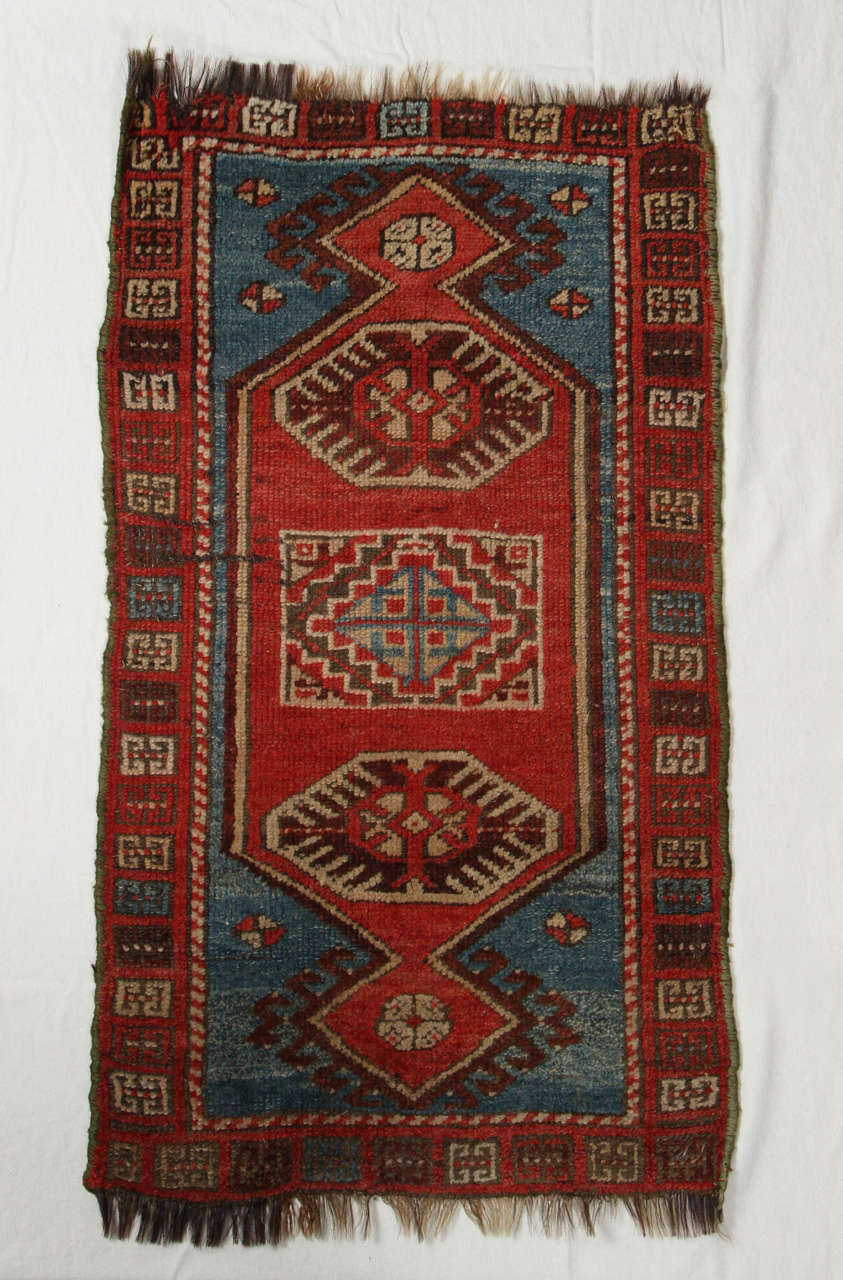 Door mat sized Turkish hand woven wool rug. Light red, blue, ivory and brown.