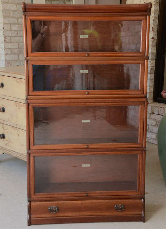 An unusual mahogany bookcase from the 1920s made by the Globe Wernicke Company (bore stamp in back identifying maker) with original tilt and slide back glass fronts and original brass hardware.