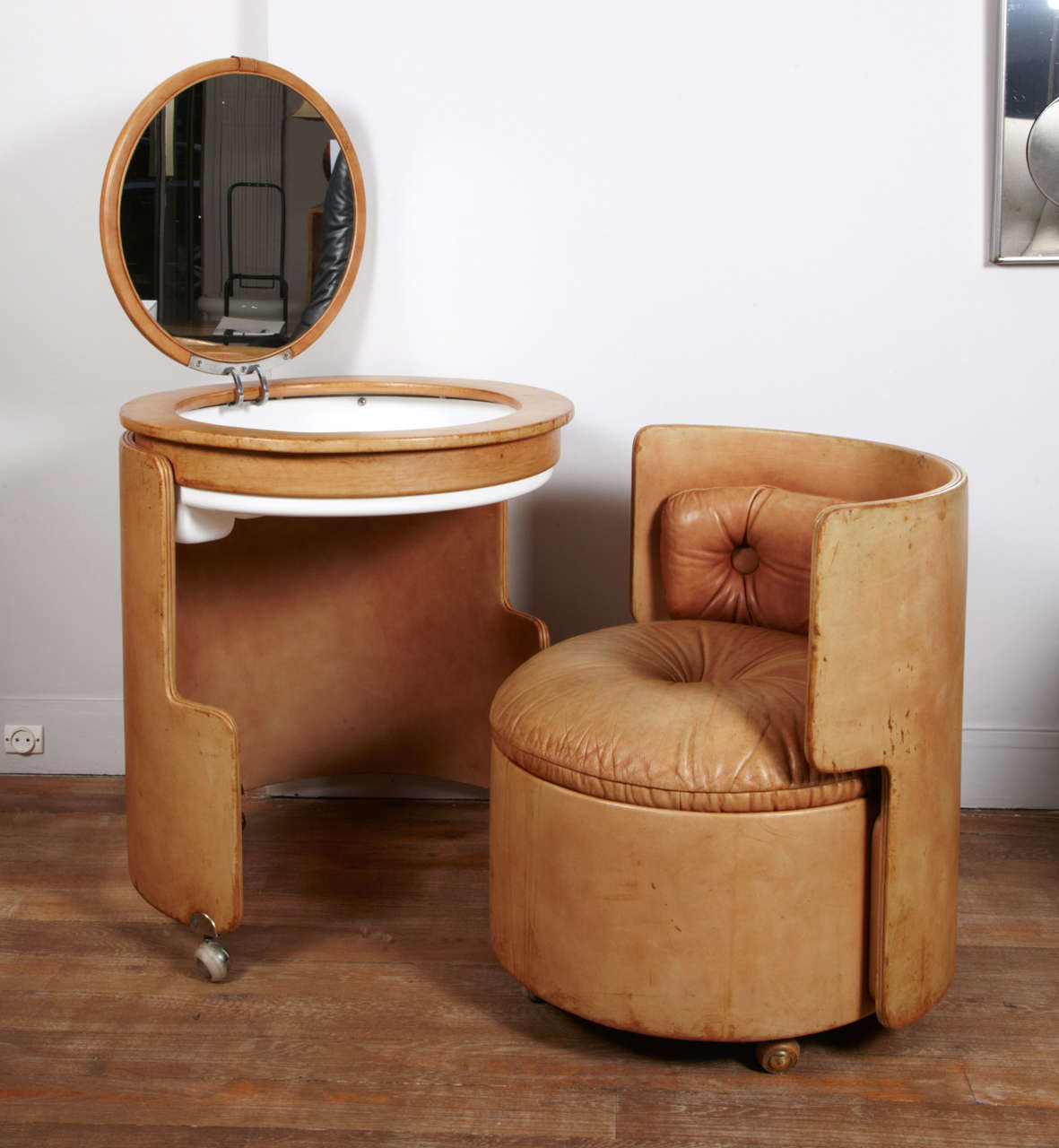 A cylindrical vanity and chair ,both entirely upholstered with leather , When closed,the seat fits nicely under the vanity to form  a gueridon .
Reproduced : G. Gramigna, « 1950/1980 Repertorio », Éditions Arnoldo Mondadori, Milan, 1985.