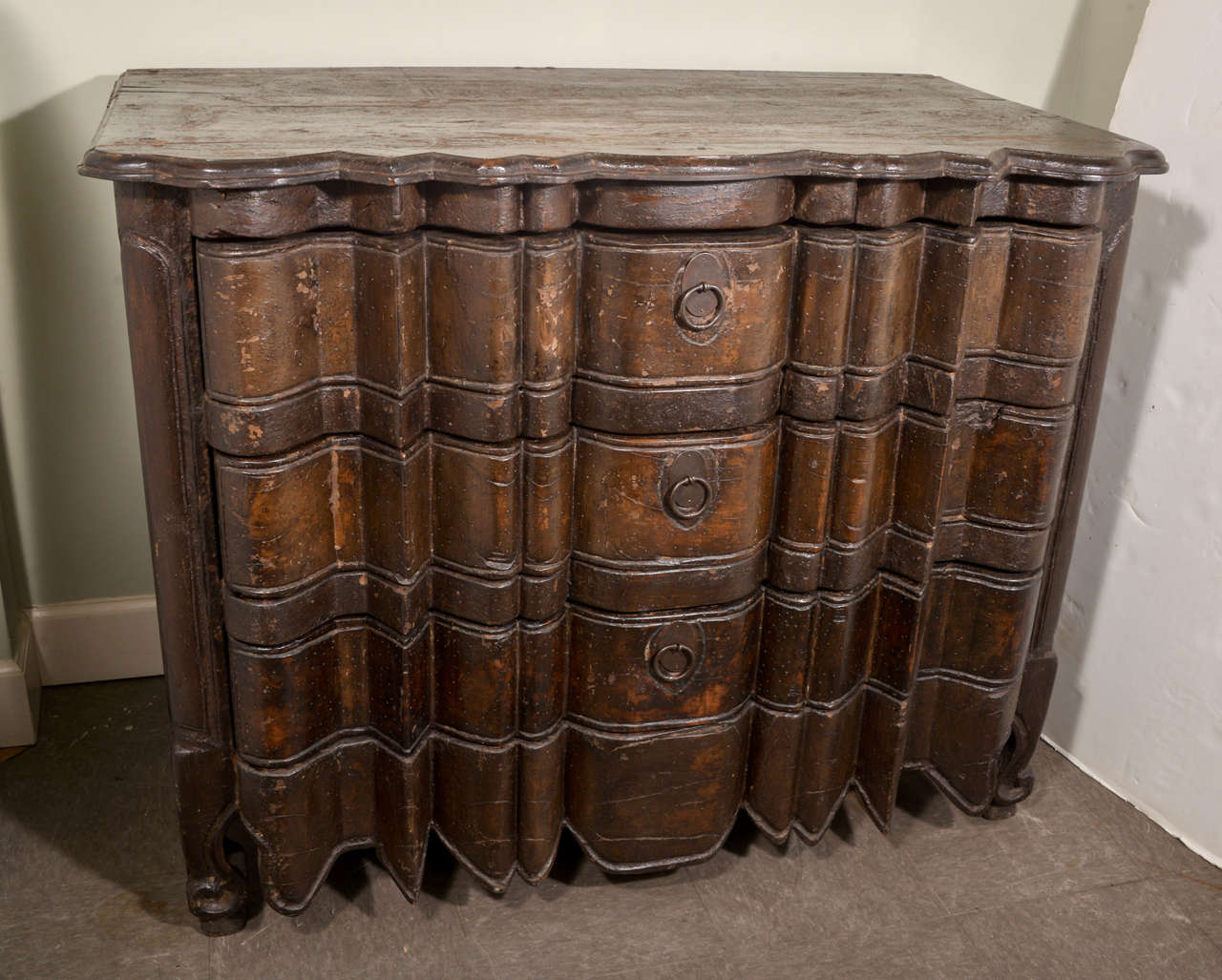 Portuguese oak commode with exuberantly shaped front and top.  Scrolled toes.  In the English Regency style of 1820.  Circa 1900.  Three deep drawers.
