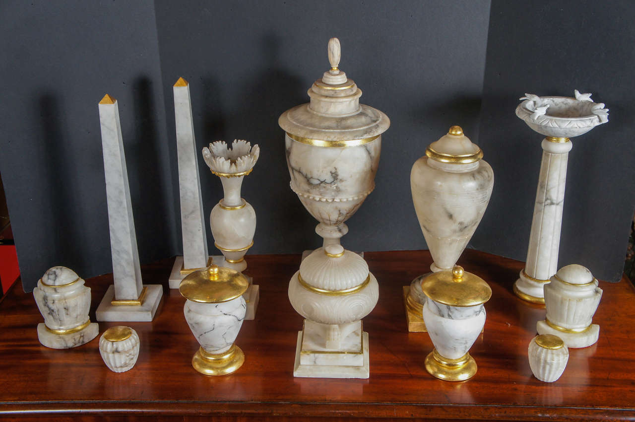 This large collection of objects that range from late 19th to the 20th century all have been decorated in some way with water gilded accents. The collection contains urns of several sizes and styles, obelisks, bookends, several sizes of covered