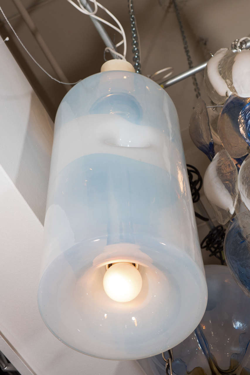 Ein transparente und modern designte Glas-Pendelleuchte der 1970er-Jahre vom Beleuchtungshaus Sothis. Originaletikett an der Seite des Schirms. Der Opalglasschirm ist mundgeblasen und hat zwei Vertiefungen an den gegenüberliegenden Seiten. In das
