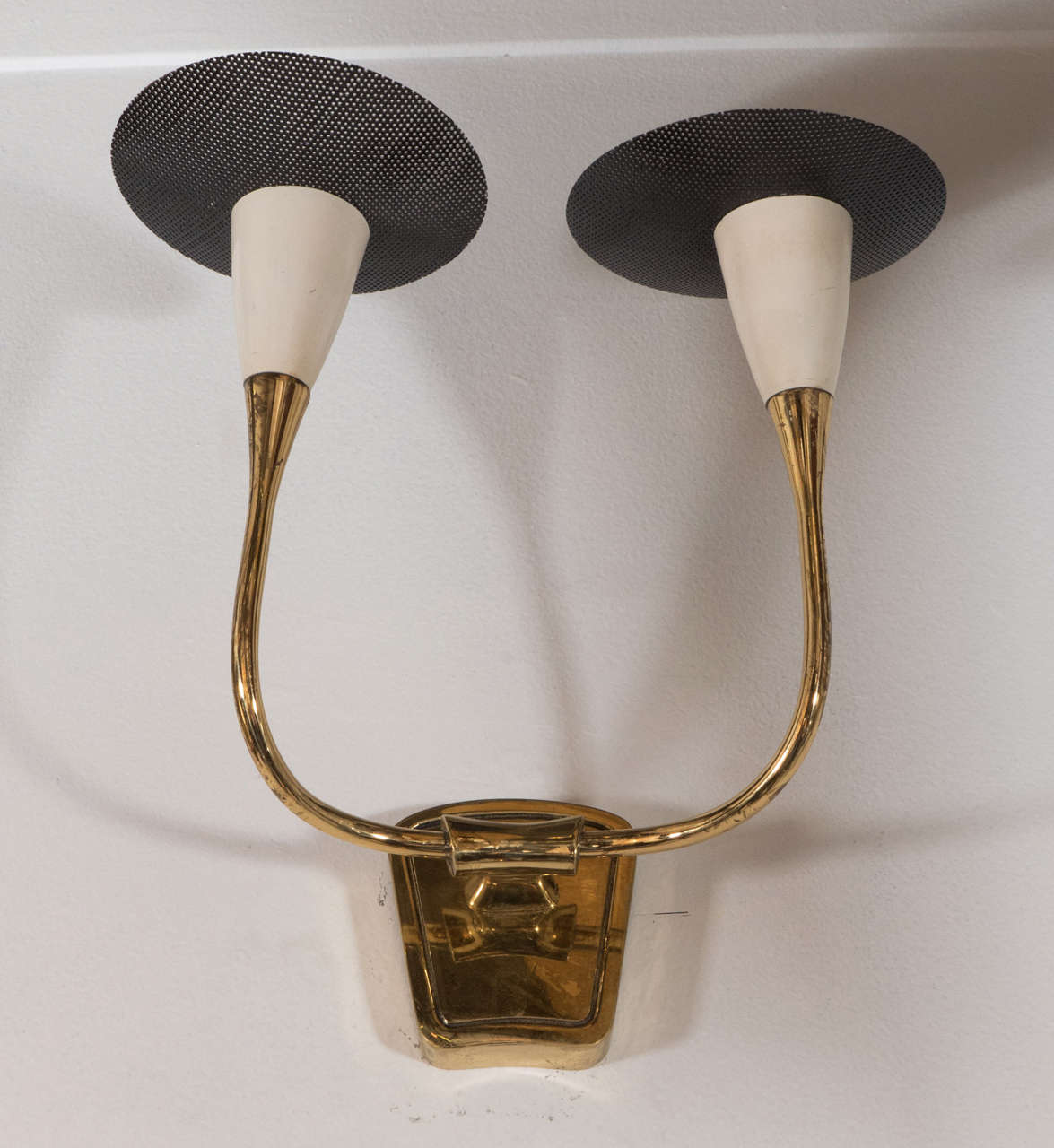 A lovely pair of French 1950s modern design brass two-light sconces. Each with ivory enamel socket covers and asymmetrical pierced metal black enamel bobeches. Brash polished and lacquered. Newly wired. Each sconce measures 11