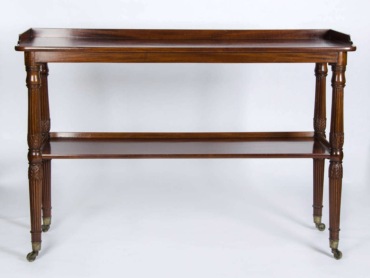 A good and extremely useful Regency period mahogany two tier buffet standing on turned, reeded and carved legs terminating in brass cap castors.