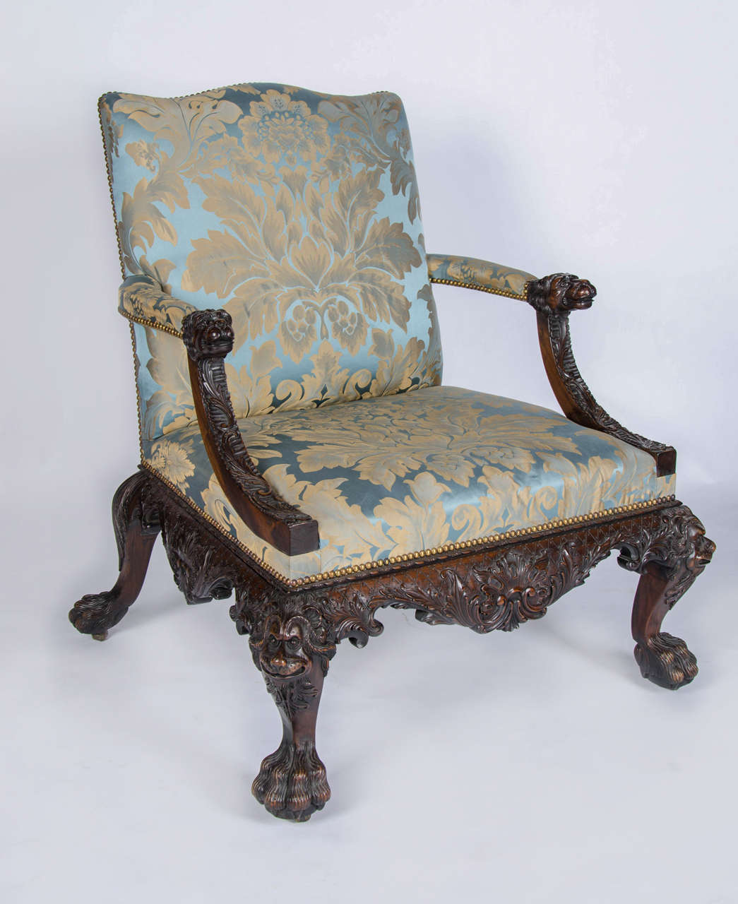 A fantastic pair of profusely carved mahogany open arm chairs in the style of Cobb and Vile.