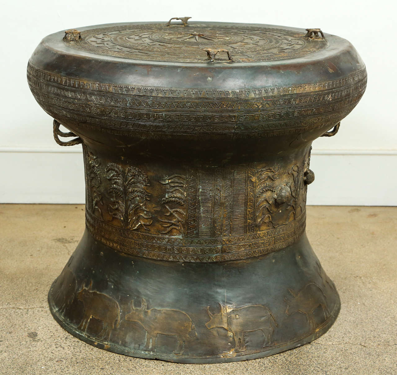 Asian cast bronze rain drum with the traditional intricate detailing and patterns carved all around both the body and the top,the top is flat centered with a raised star surrounded by concentric geometric patterned bands and with raised frog lugs.