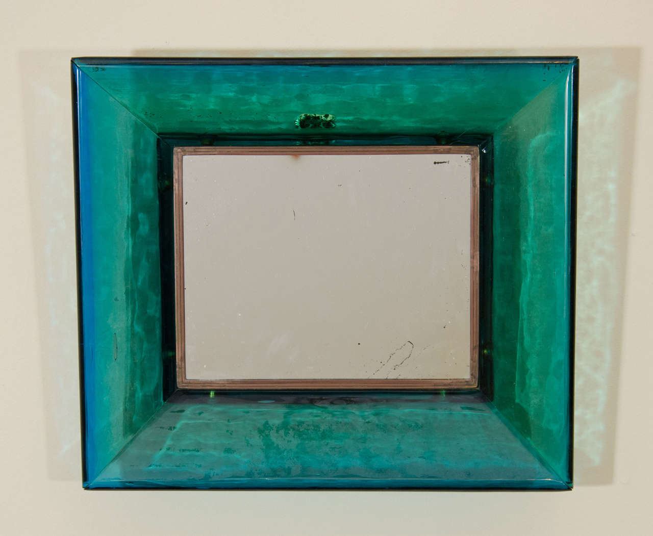 A vintage Carlo Scarpa for Venini glass frame Mid Century wall mirror. The glass frame is a blue-green color and is trimmed with bronze. There are bronze hangers on the back so the mirror can be hung either horizontally or vertically. 

Good