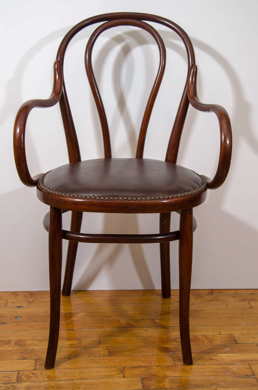 A vintage 1930s Thonet bentwood armchair. Newly reupholstered leather seat with nail head trim detailing. Good vintage condition with age appropriate wear.  Some very faint scratches to the wood.

Reduced from: $1,250