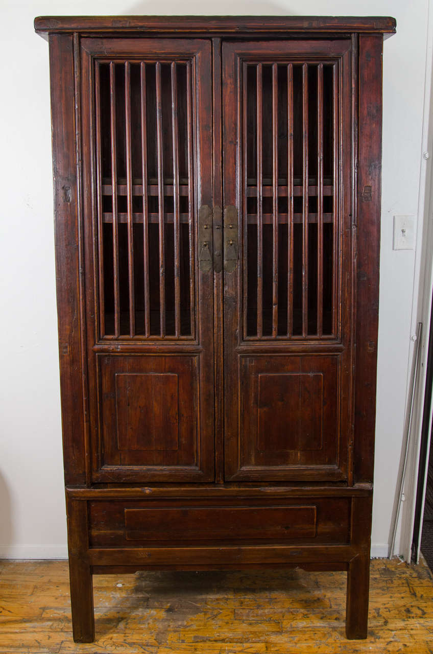 A 19th century tall Chinese fruit or vegetable storage cabinet made of lacquered wood and metal hardware. All handmade and put together with wooden joints and pegs. No nails. 

Good condition with age appropriate wear.  Some warping to one side