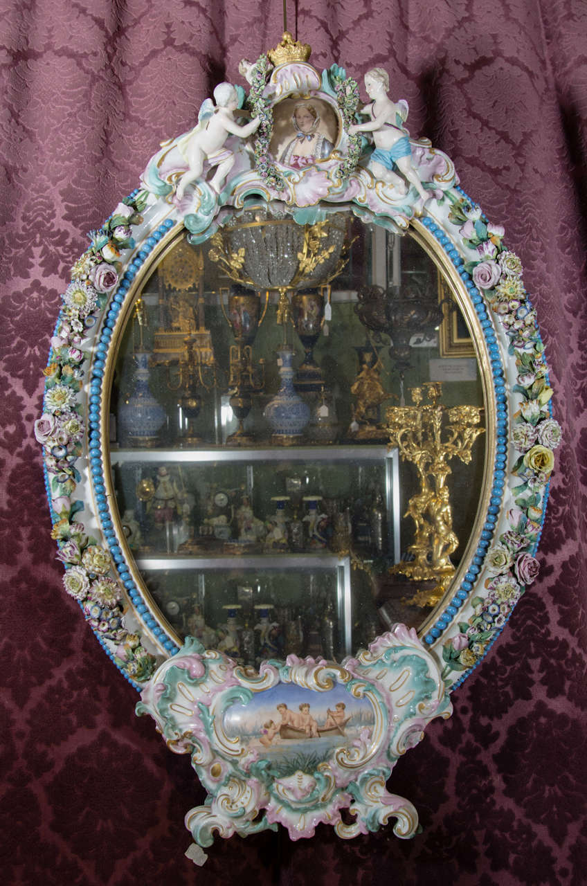 A German Meissen or Dresden oval porcelain mirror with floral decoration and figures of cherubs. It is mounted on the original wooden easel to stand, or it can be hung.