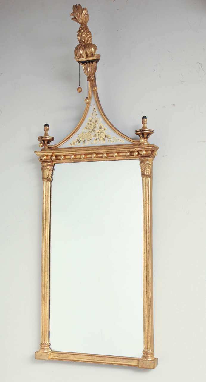 A pair of American Federal small scale gilt wood pier mirrors, each with pineapple finial above distinctive eglomise triangular pediment, the plate with spherule decorated cornice and flanked by corinthian columns.