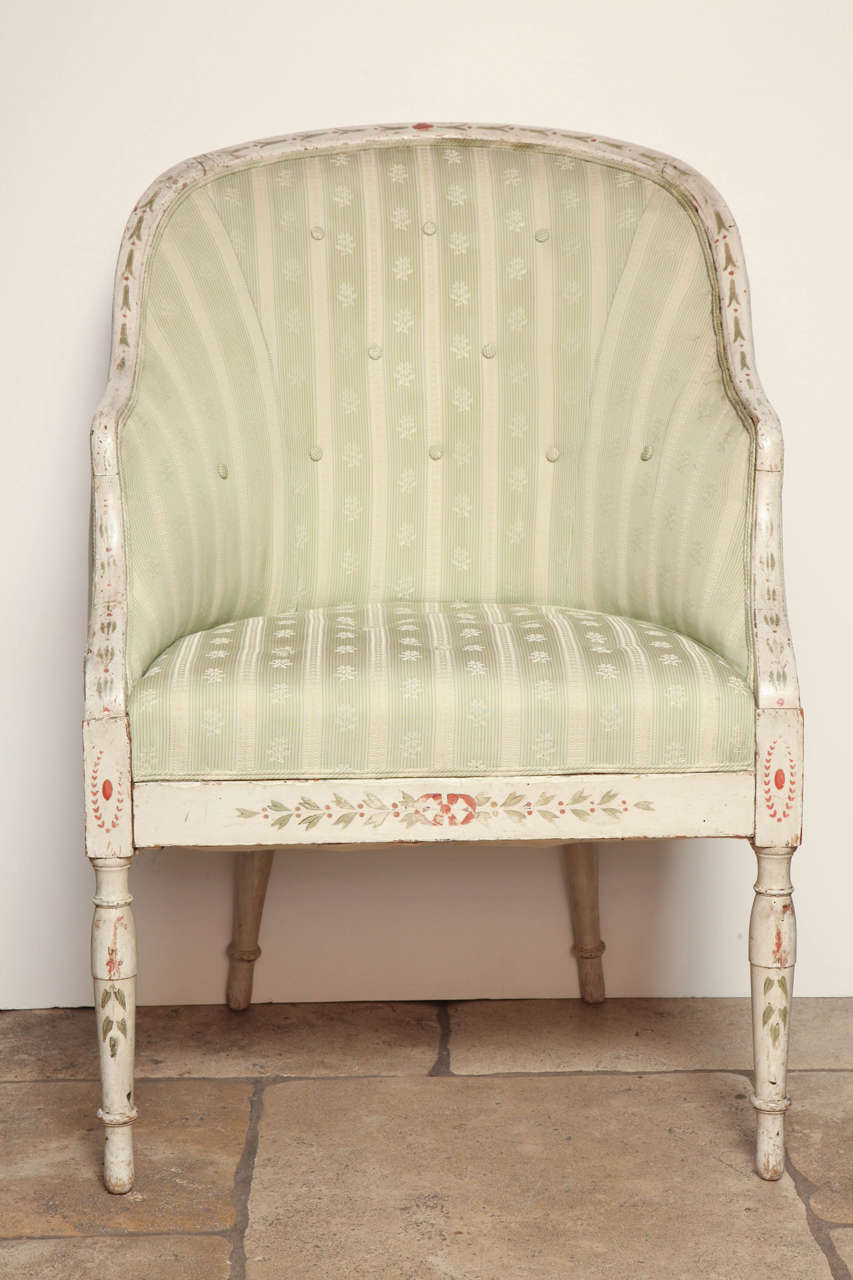 A George III Hepplewhite cream painted and green and red foliate decorated upholstered tub bergere on tapering turned legs.