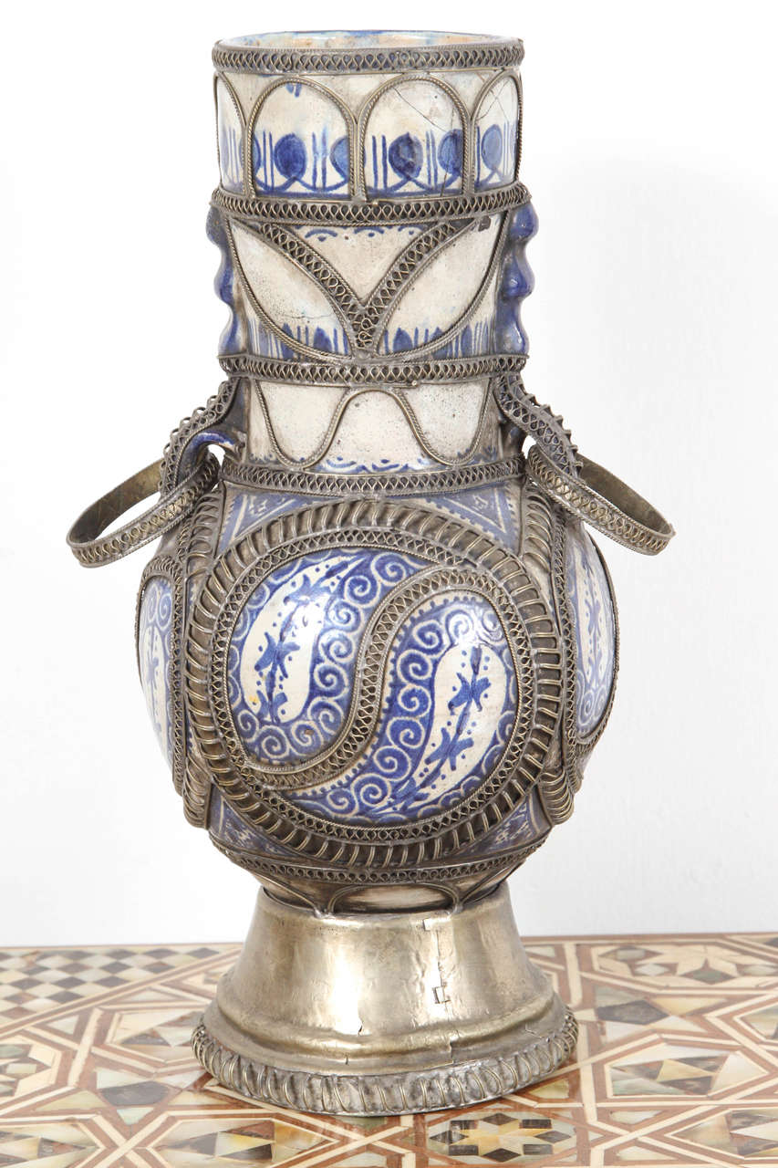 Fabulous handcrafted antique Moroccan blue and white footed ceramic vase in Moorish style.
 Adorned with fine filigree silver nickel work with handles.
The white and blue color of the ceramic is renowned as bleu de Fez.
Handcrafted in Fez, Morocco