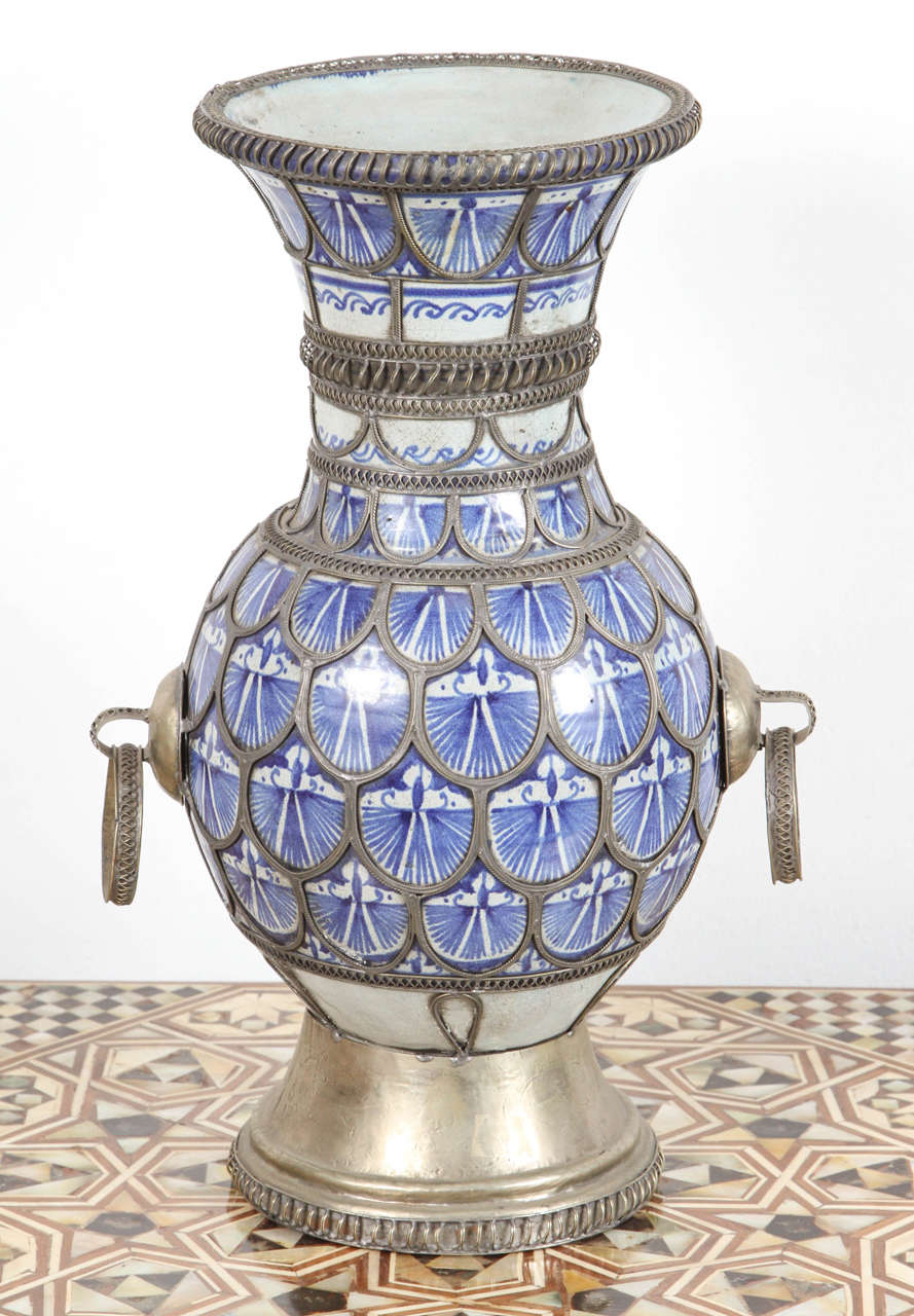 Fabulous handcrafted antique Moroccan Moorish ceramic vase in Moorish style adorned with fine filigree silver nickel work with handles.
The color of the ceramic is renowned as bleu de Fez.
Blue and white footed ceramic vase with silver filigree.