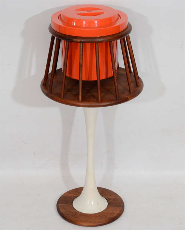 Delightful mod standing ice bucket. The orange plastic ice bucket is inserted into a walnut cradle which is supported on a tulip stand. A fun piece! 