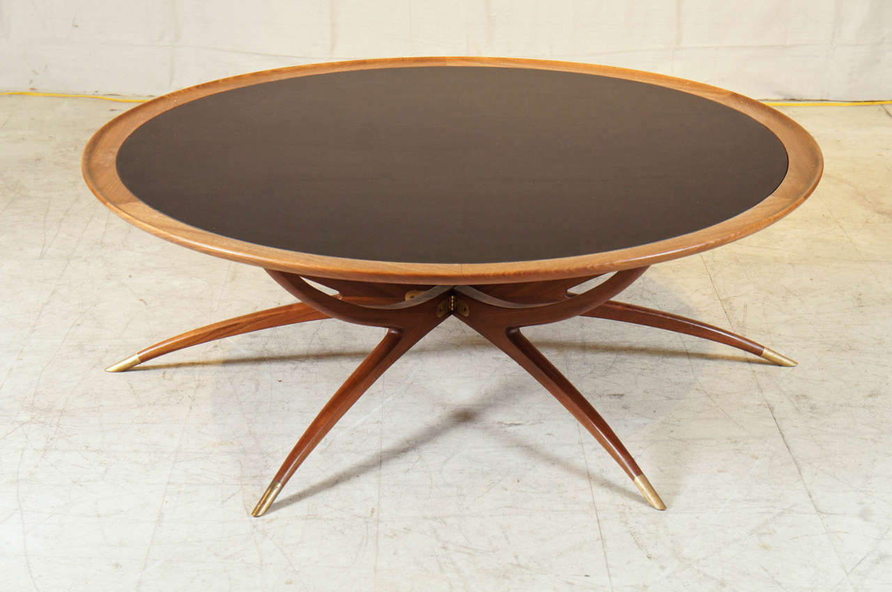 Danish mid-century modern coffee table with spider legs cuffed in brass in teakwood with black glass top