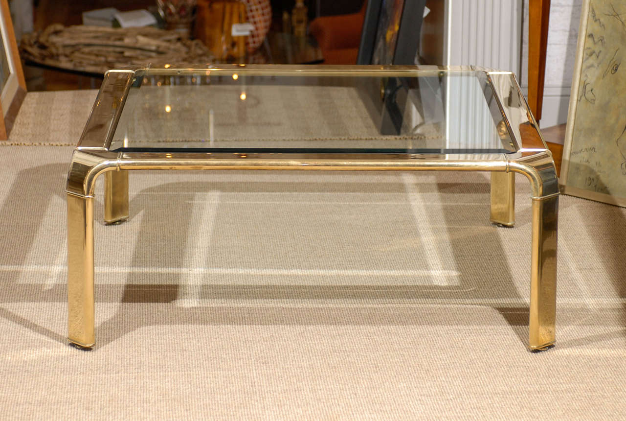 Wonderful brass and glass coffee table with a waterfall detail to the corners. Produced by John Widdicomb, circa 1970's. Retains the Maker label. Excellent Vintage Condition. There are a pair of these tables available. The price noted is for one (1)