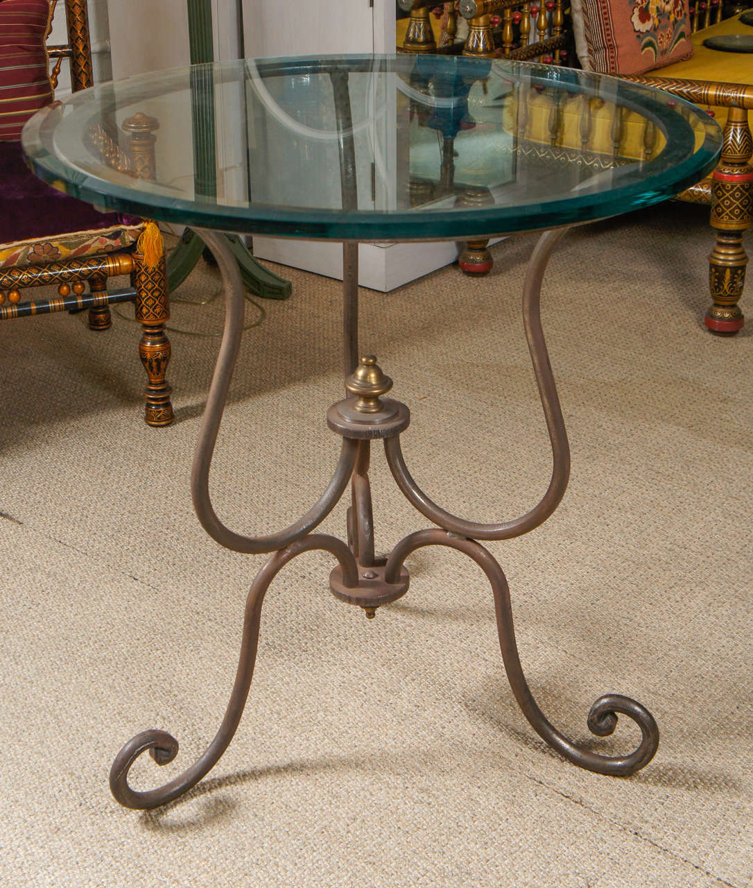 Here is an iron table with a scroll motif and a thick glass top.