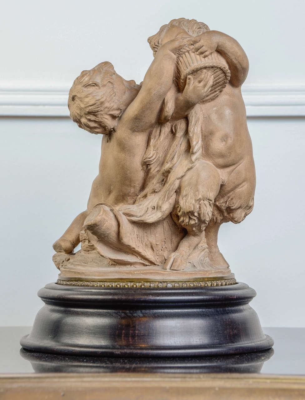 Small terra cotta group representing a putti and a young faun  arguing for a fruit basket. Carved Sevres label. Gilded bronze frieze on the base.