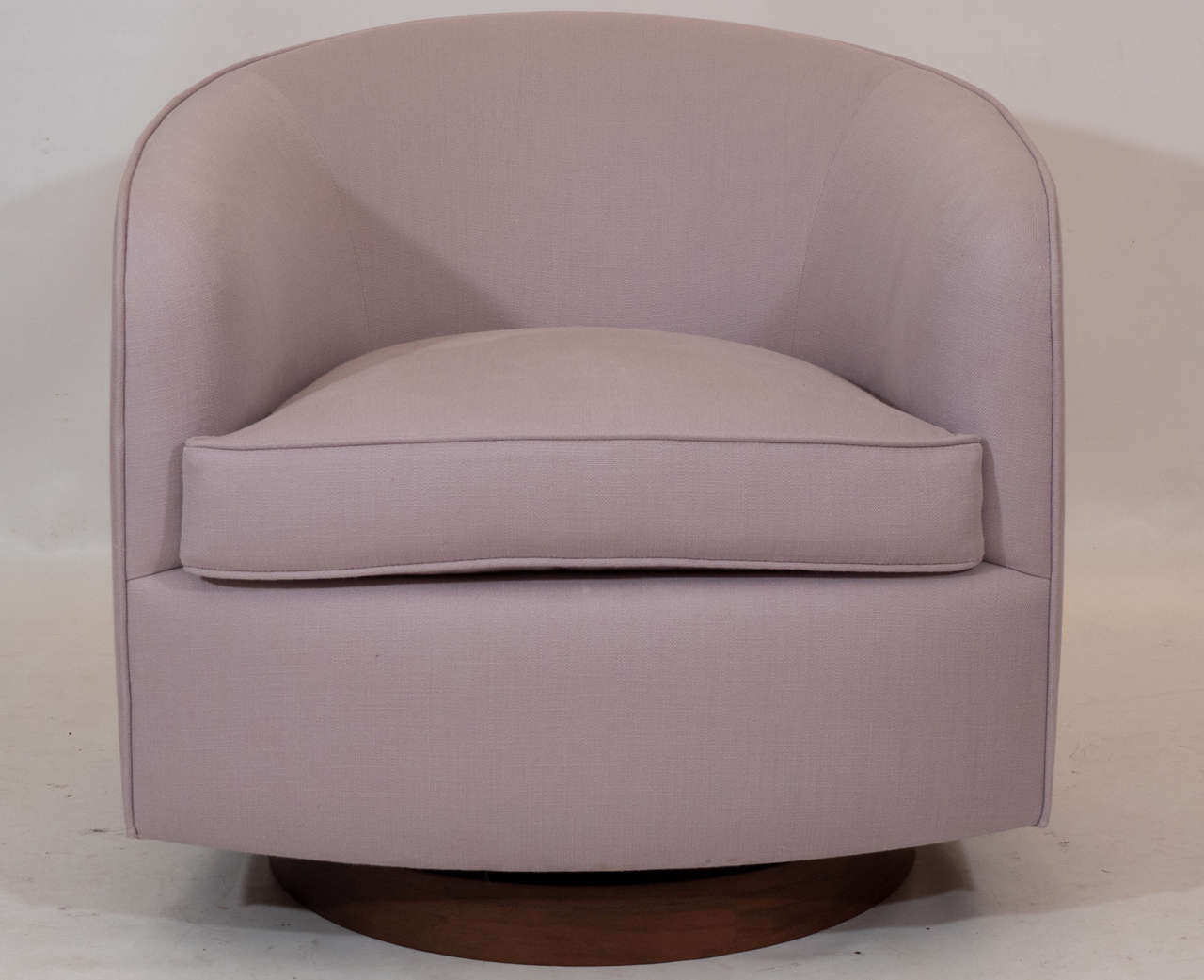 Beautiful pair of Milo Baughman swivel lounge chairs with walnut bases. The chairs are newly reupholstered in a light lavender color. The color in the photos looks a little too gray; they are lavender. Remarkably comfortable suspension and easy