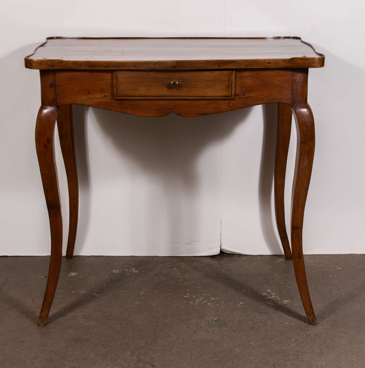 Beautiful Pearwood table with raised lip around 3 sides of the perimeter.  Lip gently fades away on the front of the table.  Single drawer and elegant tapered legs.  This table could float in a room since all 4 sides are finished.