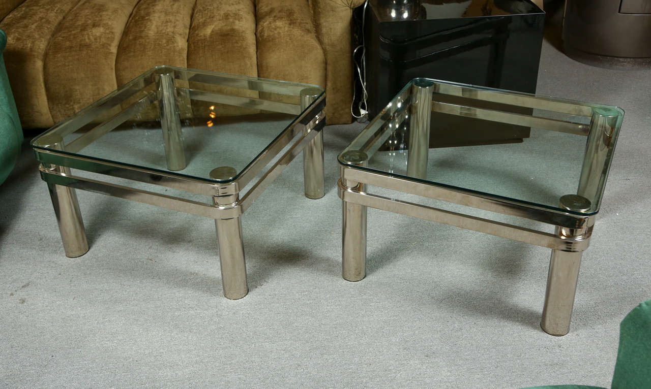 Pair of very stylish end tables.   The bases are chrome with horizontal bands connecting the cylindrical legs that support the glass tops. The tables are possibly by Pace.