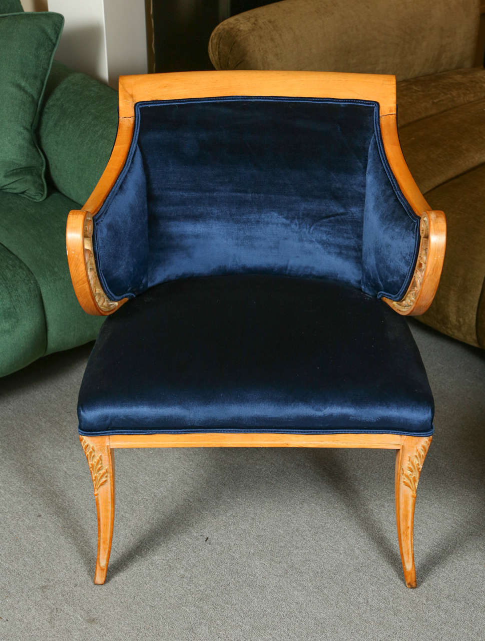 Glamorous side chair in the Hollywood regency style.  This graceful chair has a natural-finished wood frame with scrolled arms.  The arms and front legs are accented with carved leaves. It is newly reupholstered in a lovely midnight blue silk velvet.