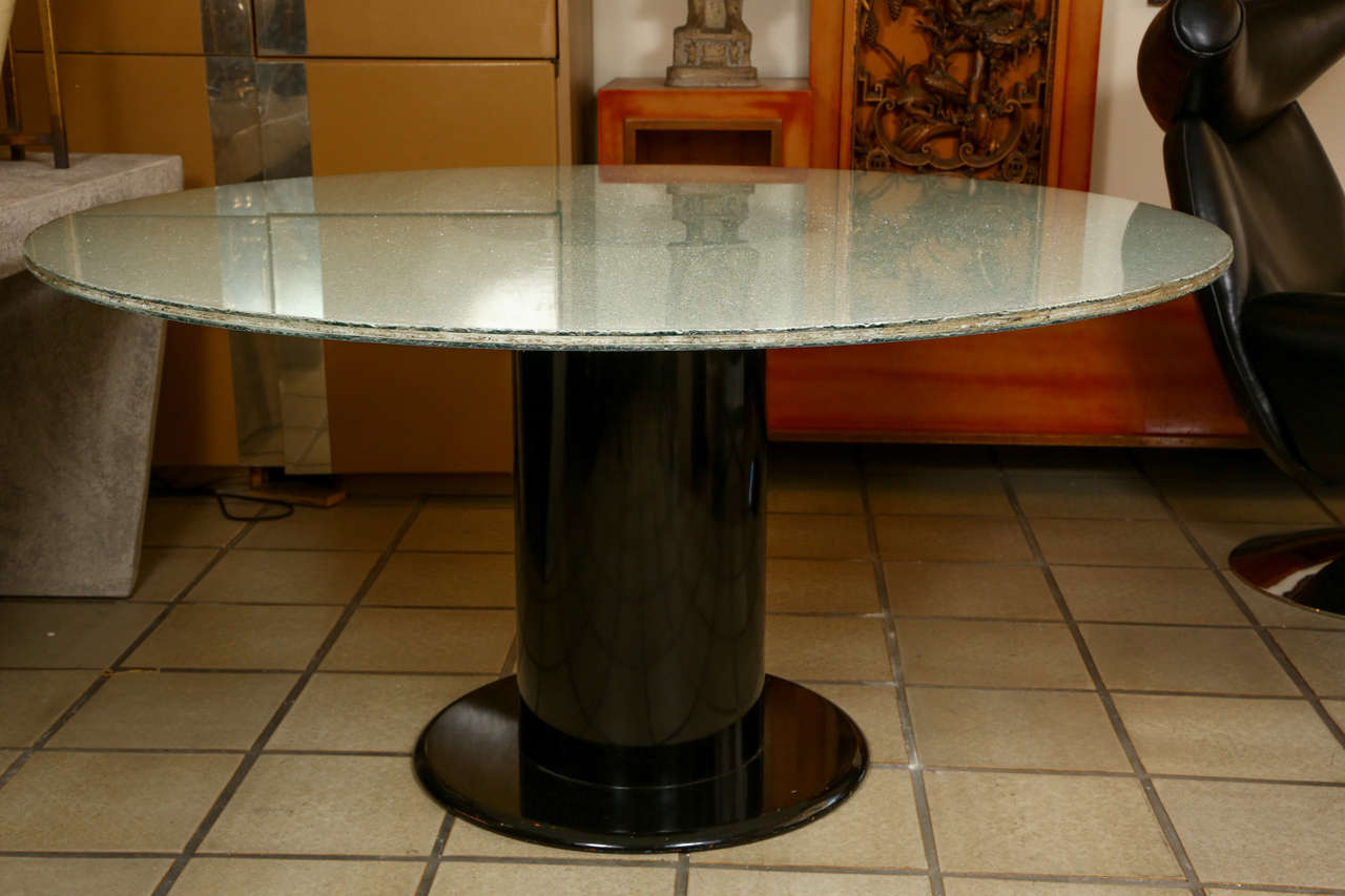 Round dining table with a glossy black lacquered wooden cylindrical base. The table top is acrylic with a crackled layer between two smooth layers. 
The crackles radiate from the center for a wonderful effect and when the light hits it, the top is