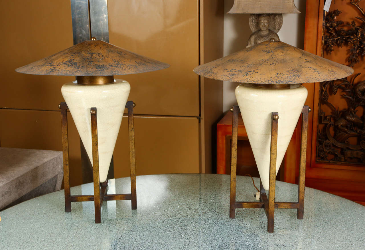 Pair of unusual table lamps with cone-shaped ceramic bases supported by metal cradles. The ceramic has a beautiful crackle glaze and the cradles have an antique brass finish. The metal flattened coolie shades have a mottled leafed finish.
Shade