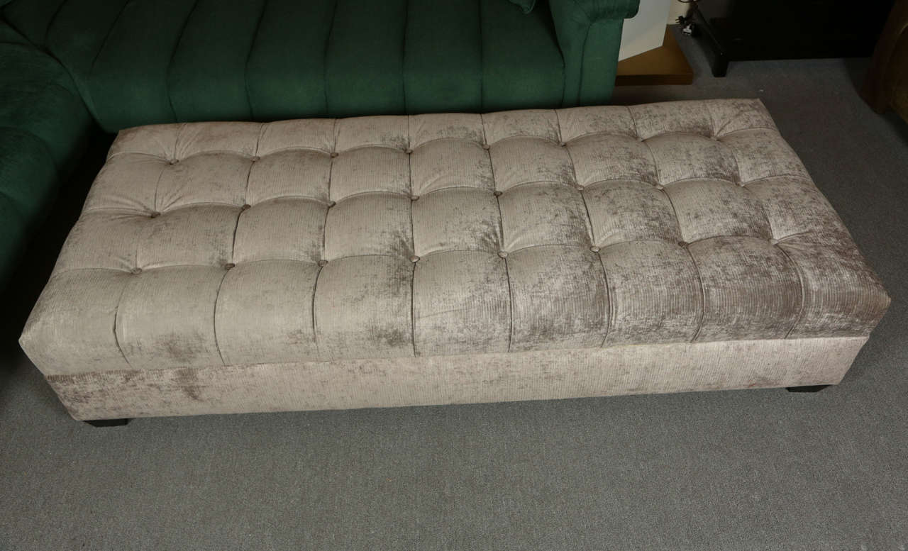 Large beautiful biscuit tufted ottoman.  The ottoman is  newly reupholstered in a silvery gray velvet fabric.   The bench is up on four very short legs.