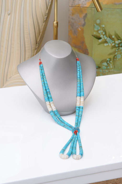 Native American style double-strand necklace with coral and turquoise beads. Top of necklace is double stranded and tapered out from the centre. Large double beaded turquoise knot flanked by coral beads on the bottom, continuing into twin