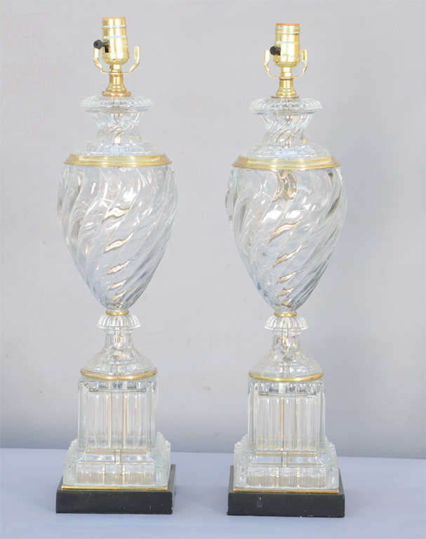 Pair of Baccarat style glass lamps, by Paul Hanson; each having swirling glass vase with brass collar, raised on square fluted plinth and black marble base.
