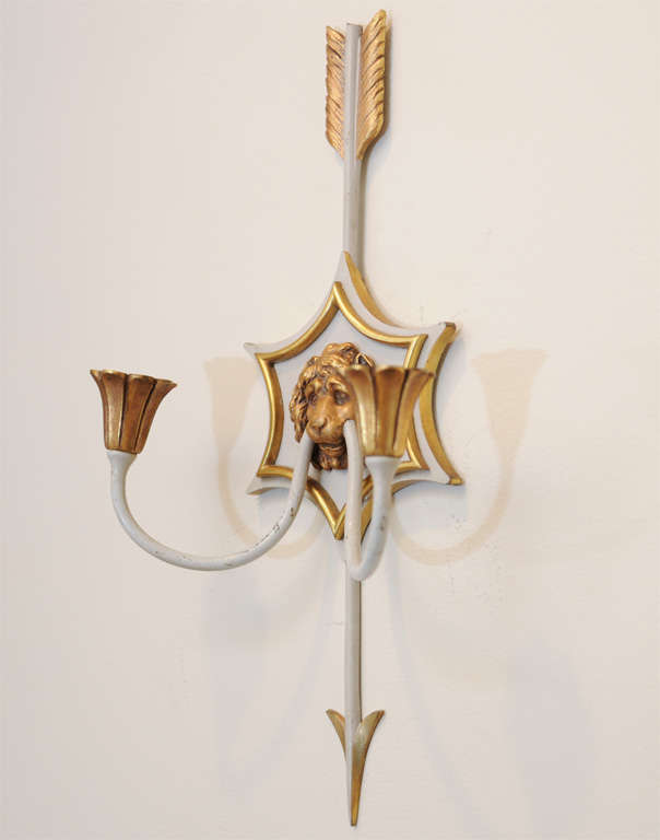 Very fine pair of sconces, of gilt bronze and partial painted finish, each concave hexagonal backplate divided by a vertical arrow, and centered by a lion mask, its teeth holding two C-scroll arms terminating in fluted candlepots.  Presently, not