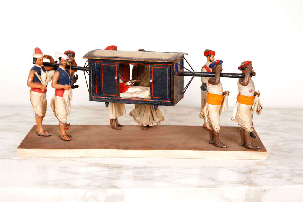 An Anglo-Indian painted terracotta and wood sculptural group of a palanquin with an East Indies Company Officer being carried by four servants, Calcutta or Krishnanagar.