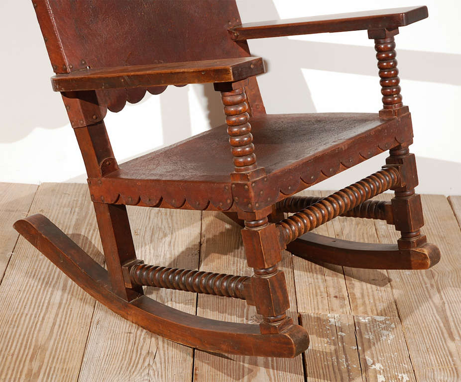 Beautiful antique Mission style wood and leather rocker.  The leather seat and back has scalloped edge detail and brass nails, the wood frame has hand turned spindle details.