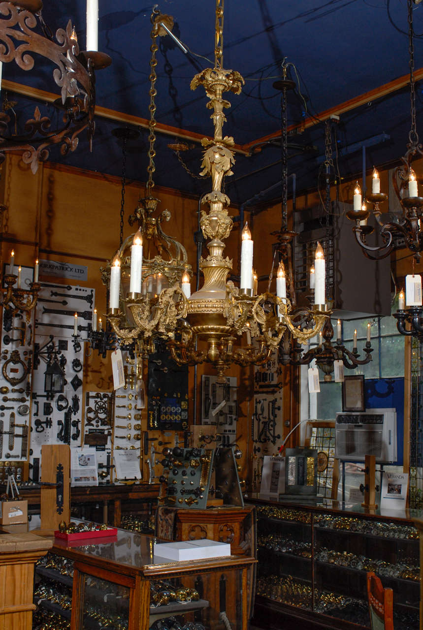 Early 20th Century English Gilt brass wired chandelier with intricate foliate details.  This fixture includes 6 lights on delicate arms adorn with a vine and leaf motif.  The balaster center of the chandelier showcases several tiers of