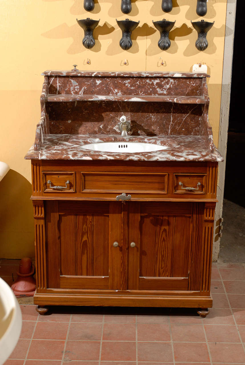 19th Century French pine and marble washstand sink.  The pine washstand has two lower cabinet doors, as well as two side drawers, which allow for ample storage.  The porcelain sink is set beneath the marble counter.  This piece still features the