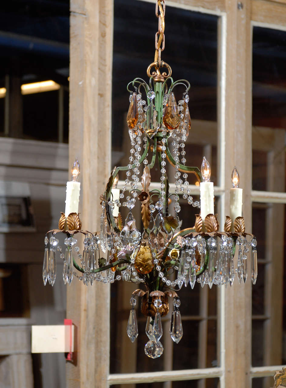 Pair of whimsical early 20th Century Italian iron, crystal, and porcelain wired chandeliers.  Each fixture has 4 candles resting in leaf-like painted metal  holders.  Each candle holder is adorned with clear rosette and tear drop crystals.  Clear