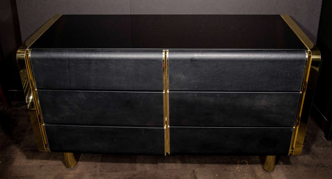 Ultra modern and sexy dresser with streamline design. The dresser has a polished brass banded frame and has black leather drawer fronts as well as a smoked black glass top. Fitted with six spacious drawers, the chest of drawers has sleek rounded