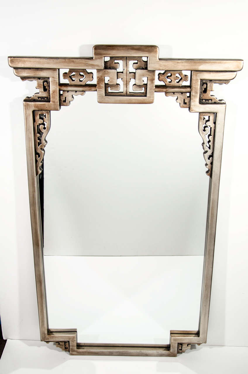 Exquisite modern mirror with Asian inspired design. The mirror has a refined pagoda design with hand applied antique silver leaf finish over resin and wood.  This mirror is rectangular in form and features intricate hand carved motif details. 