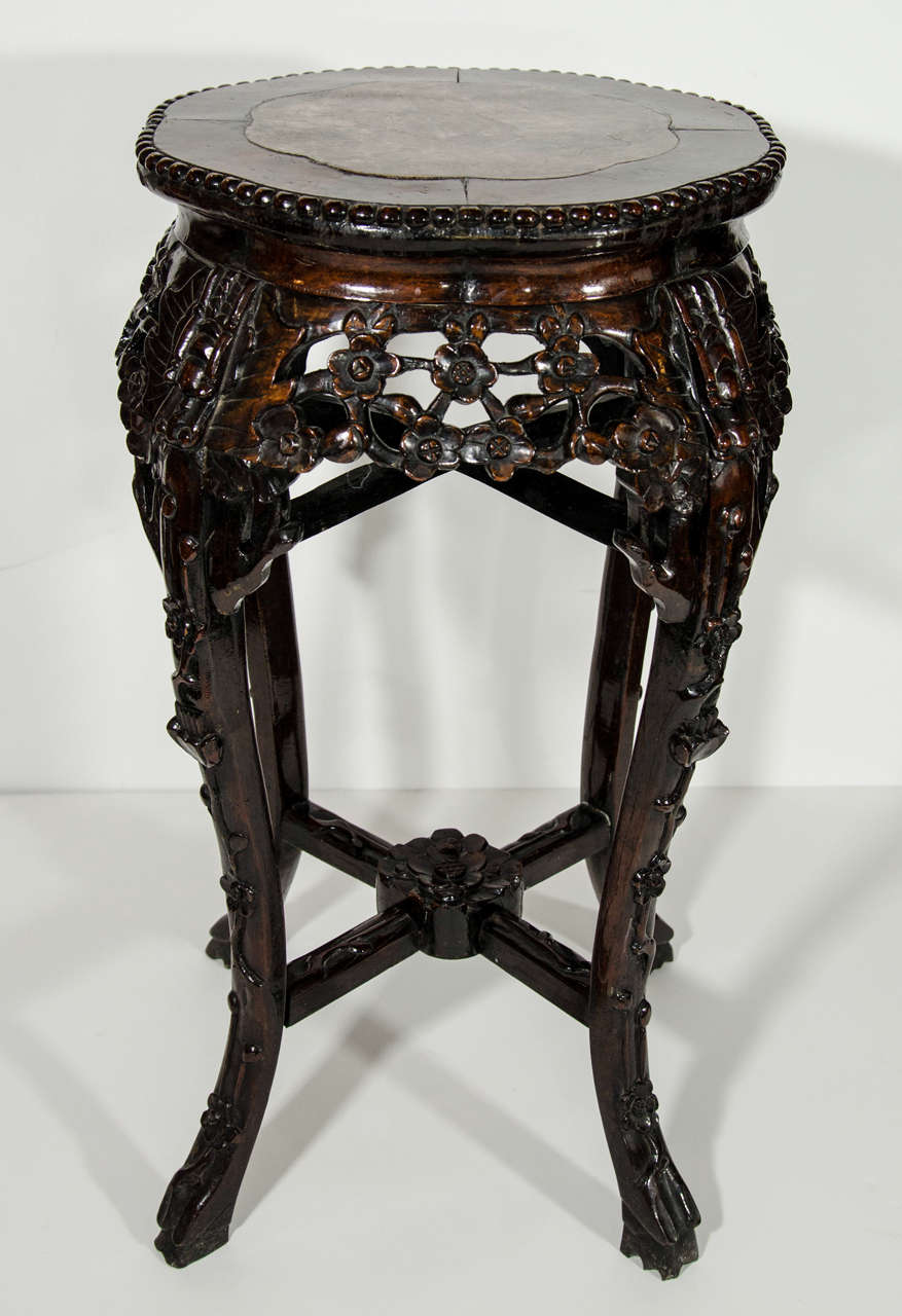 Exquisite hand made pedestal stand or side table in Chinese hardwood. The table has intricate hand carved details throughout, featuring a variety of Asian floral motifs. The table also has a sinuous top design reminiscent of an octagon form, and