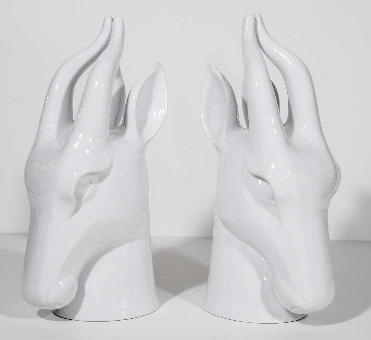 Pair of highly stylized ceramic gazelle or ibex sculptures in a white porcelain glaze finish (blanc de chine). The sculptures have a modernist form and and truly beautiful from all angles.  Make great desk or bookcase decorative objects.
